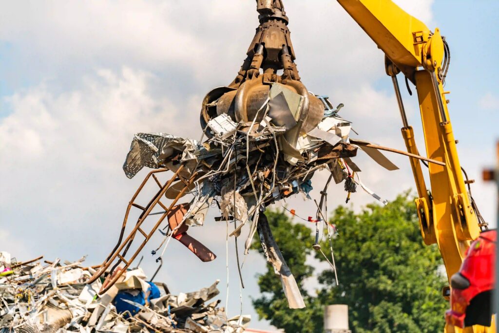 Excavator lifting scrap metal for recycling, showcasing services by scrap metal recyclers Wilmington, DE, A1 Dumpster Rental.